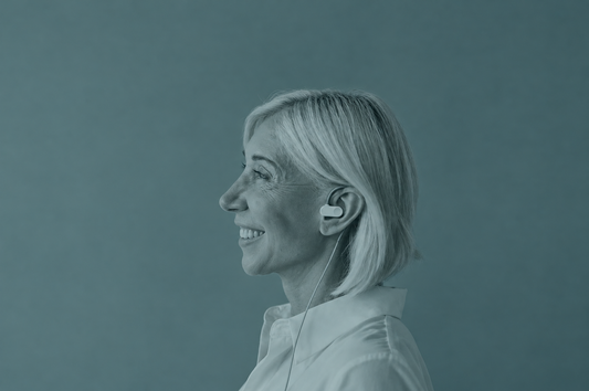 Smiling woman in profile wearing a white Nurosym earpiece, a subscription-free vagus nerve stimulator
