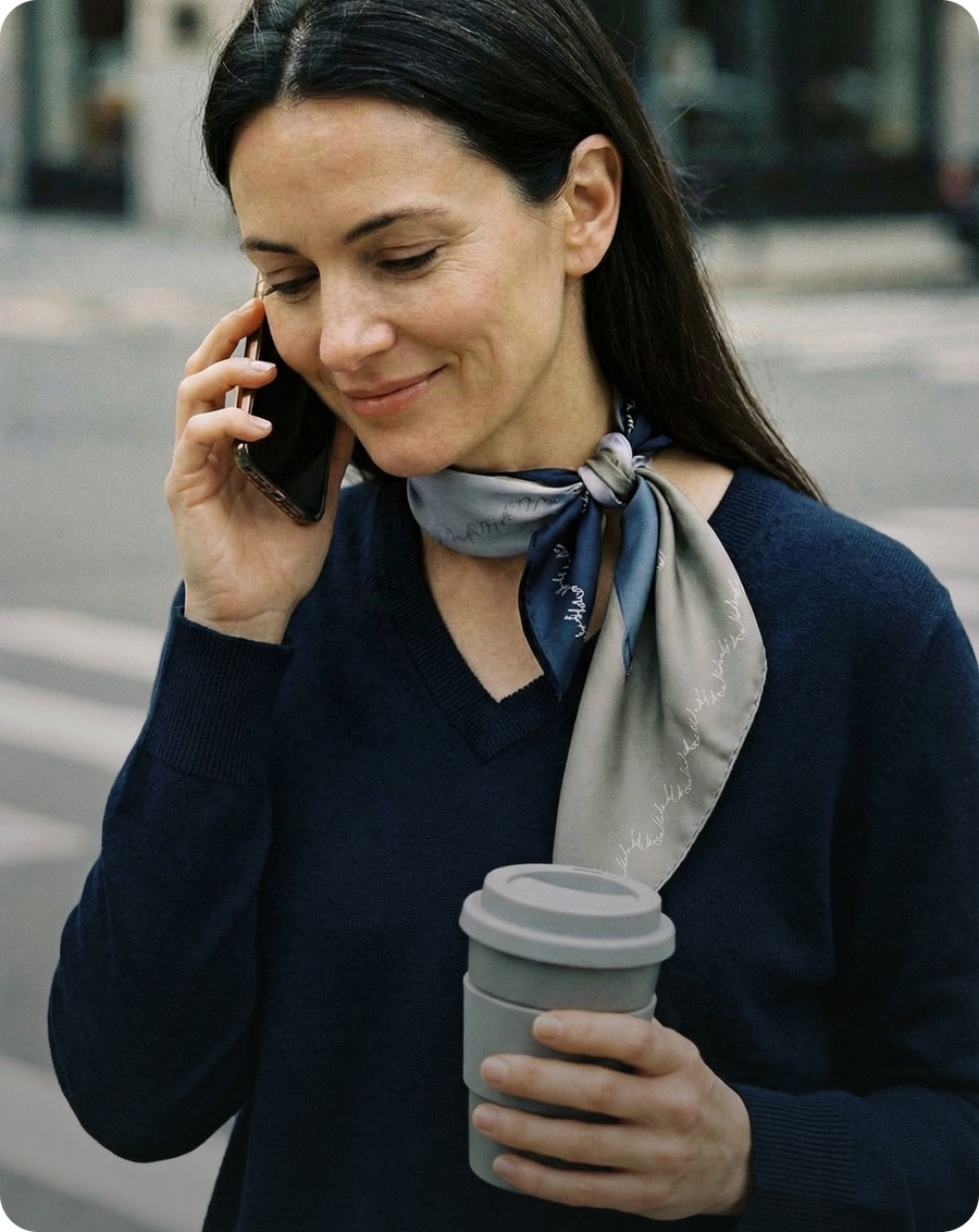 Woman on a phone call holding a coffee cup on a city street