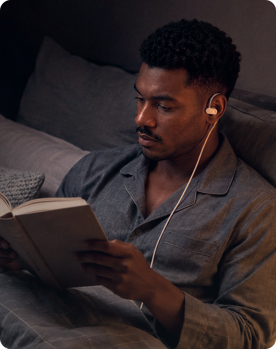 Man reading a book in bed while using Nurosym