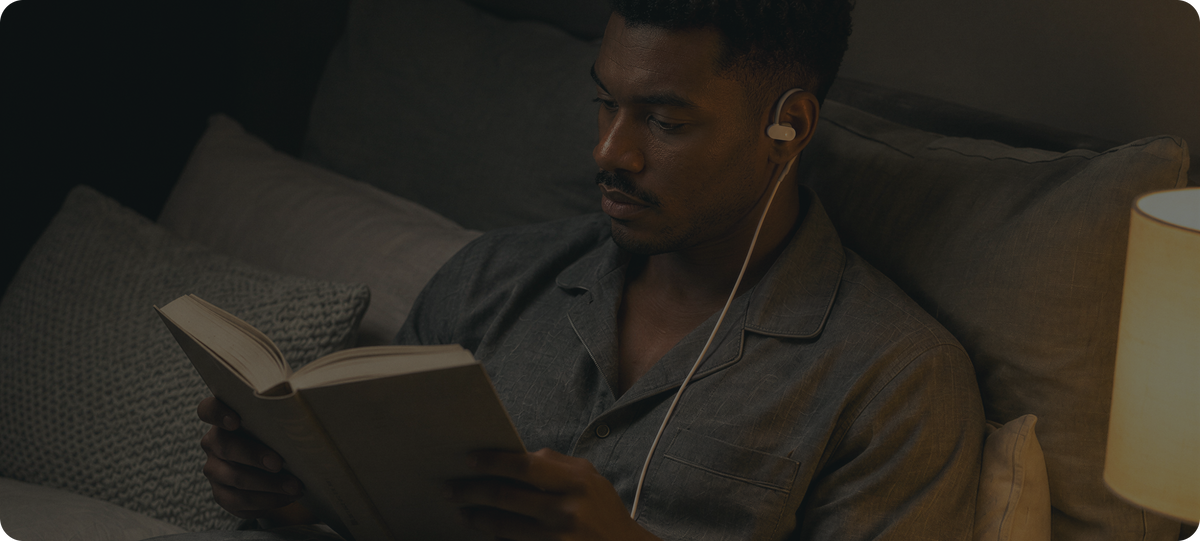 Man reading a book in bed while using Nurosym